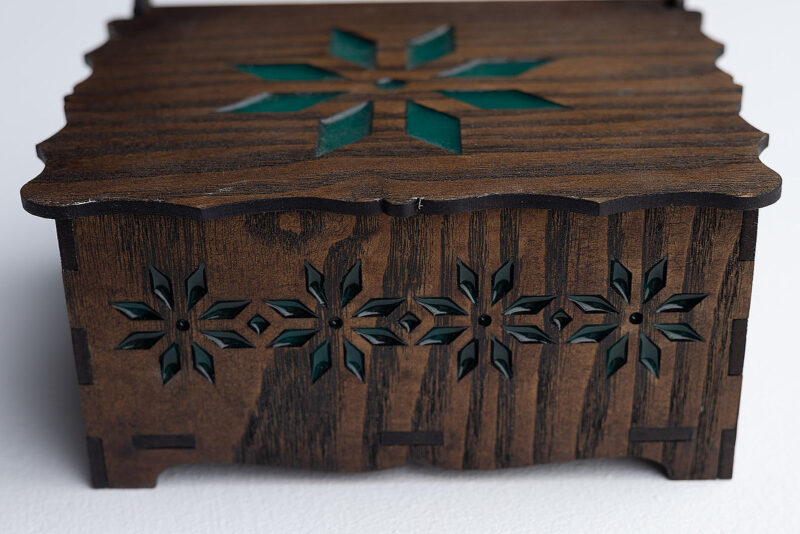 Detalle del lateral calado con motivos florales de joyero de madera y resina verde.