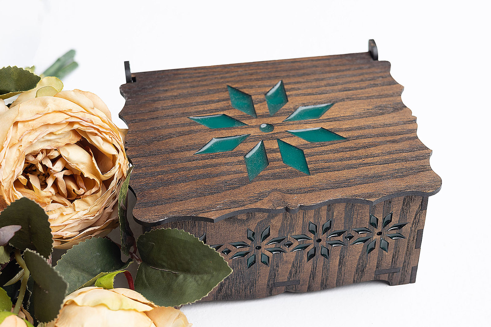 Detalle del lateral calado con motivos florales de joyero de madera y resina verde.