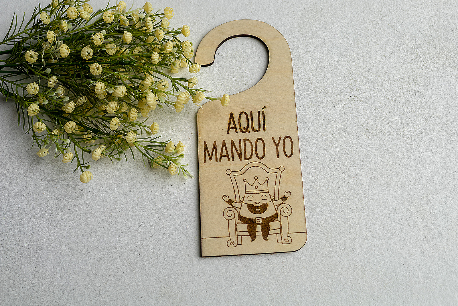 Colgador de puerta divertido Aquí Mando Yo con dibujo de rey en el trono.