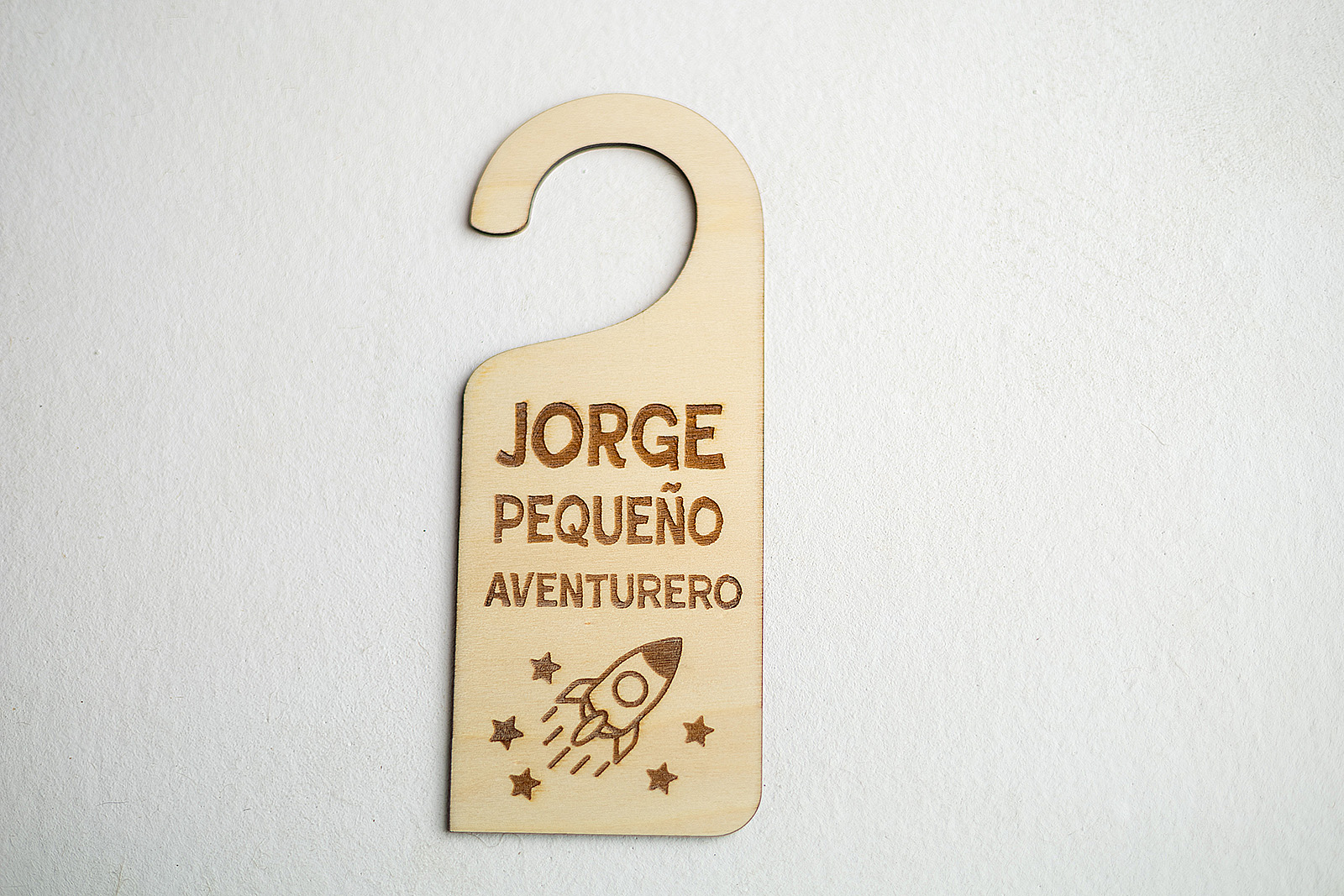 Colgador de puerta infantil personalizado Jorge Pequeño Aventurero con cohete espacial.