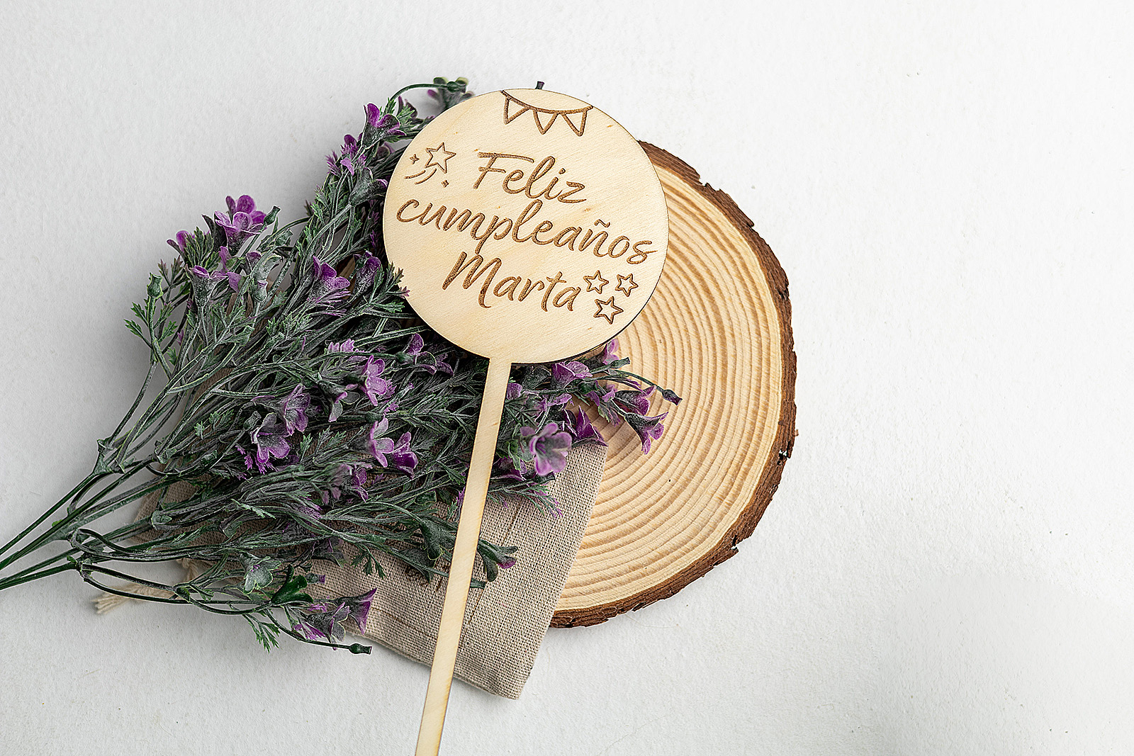 Vista superior de topper de madera para tarta de cumpleaños sobre base de tronco natural.