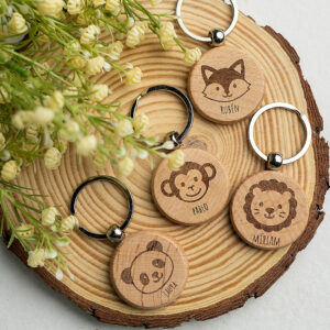 Colección de llaveros redondos de madera con caras de animales: zorro, mono y león.