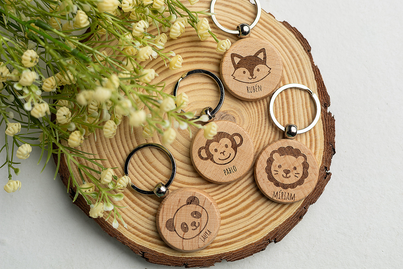 Colección de llaveros redondos de madera con caras de animales: zorro, mono y león.