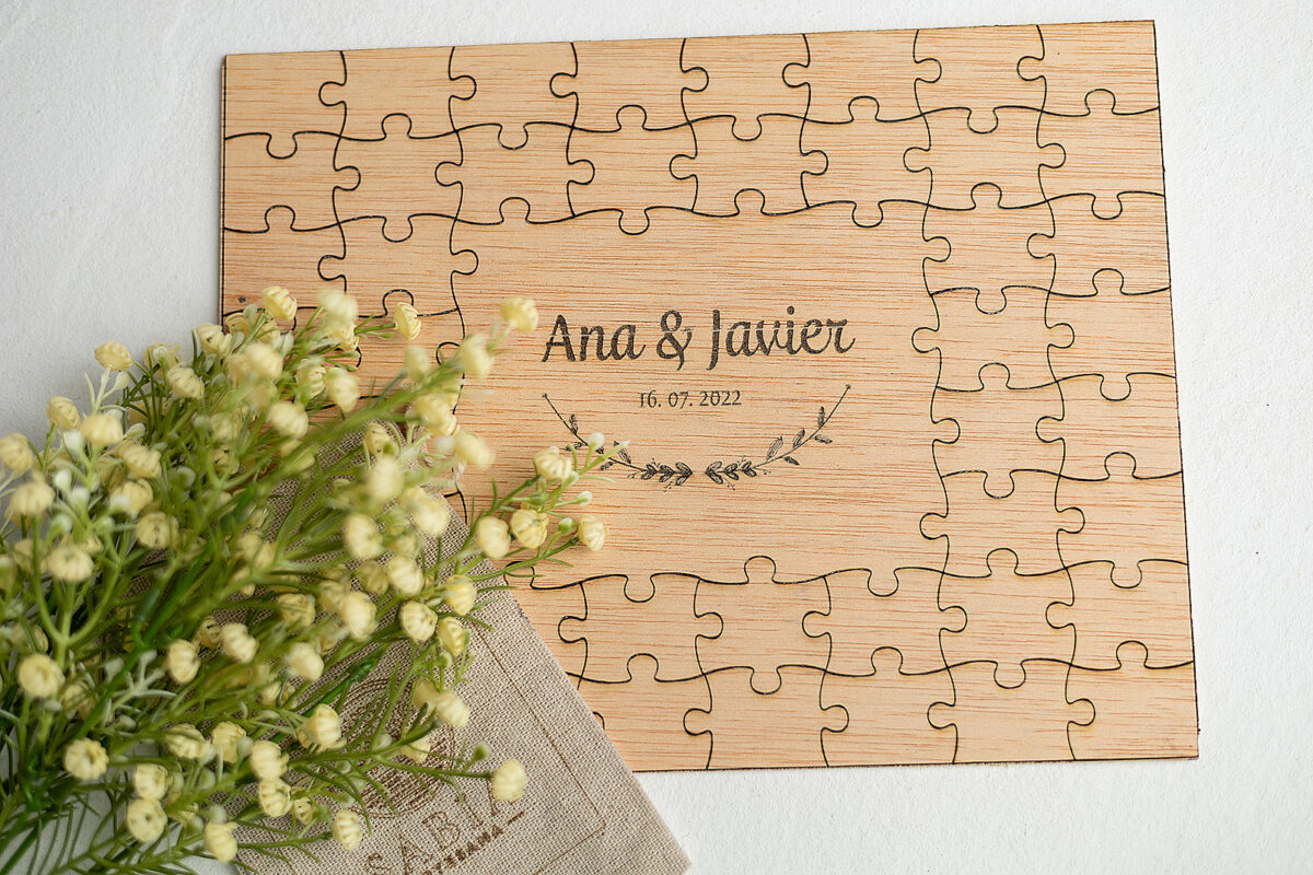 Libro de firmas de boda original en forma de puzzle rectangular de madera, personalizado con los nombres "Ana & Javier" y la fecha.