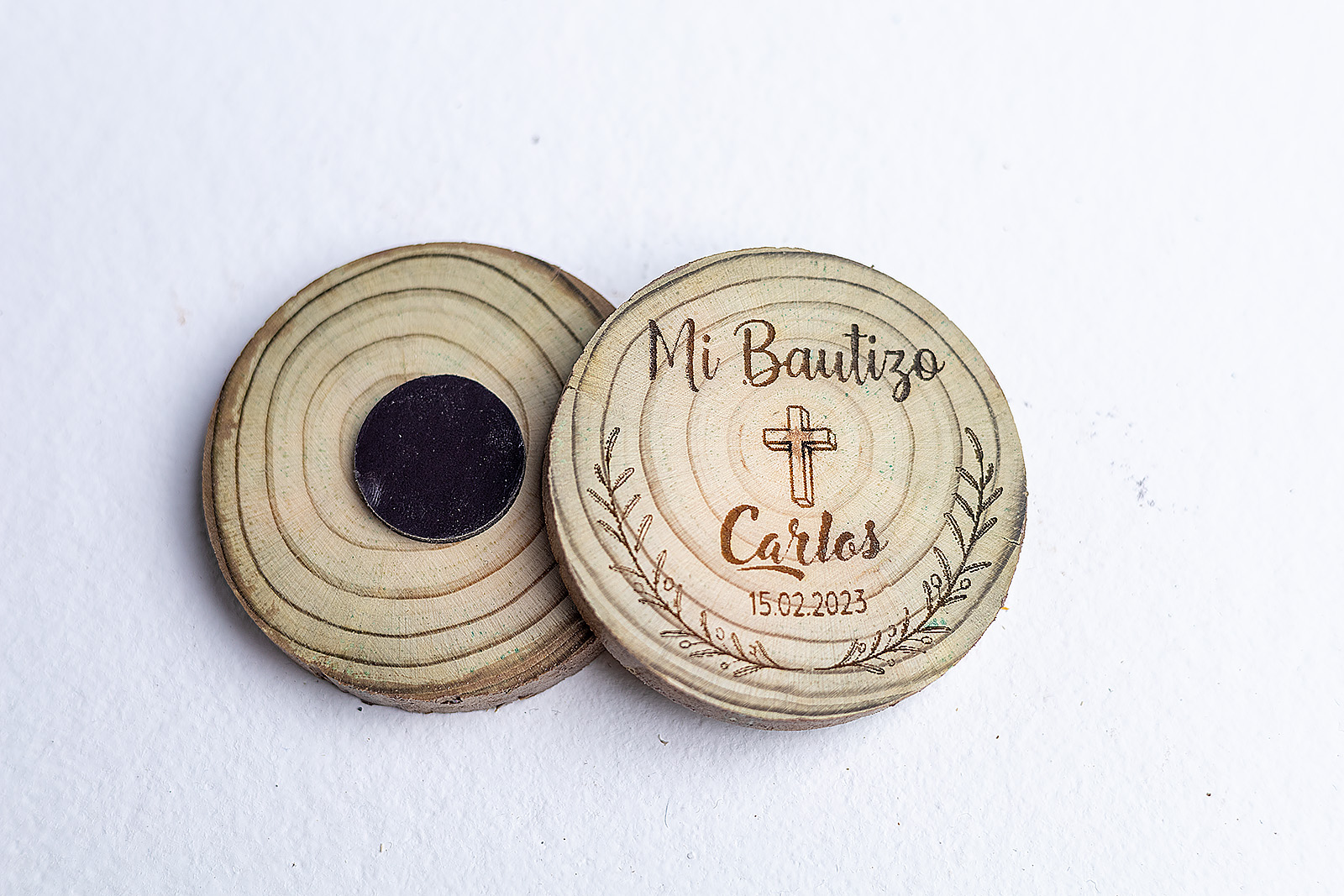 Imán de rodaja de madera natural con corteza grabado con diseño Corona de Fe, cruz y nombre Carlos para bautizo, vista frontal y trasera.
