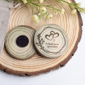 Primer plano de un imán de madera para boda con diseño geométrico y corazones grabados, personalizado con nombres Sofía y Javier, con imán potente.