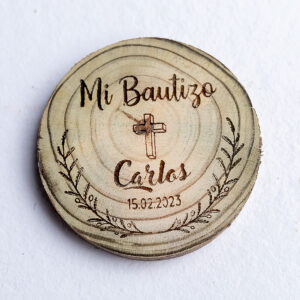 Imán rústico de madera para recuerdo de bautizo, con un grabado láser de una cruz dentro de una corona de laurel y personalizado con el nombre Carlos.