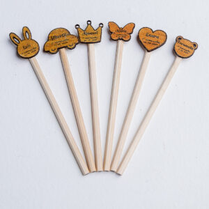 Lápices de madera personalizados como recuerdo de comunión para niños, mostrando los diferentes diseños de adorno: conejo, coche, corona, mariposa, corazón y oso.