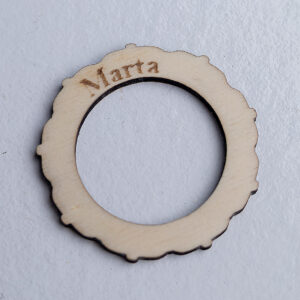 Vista en perspectiva de un anillo servilletero de madera para boda, mostrando el grabado del nombre Marta y el borde ornamental.