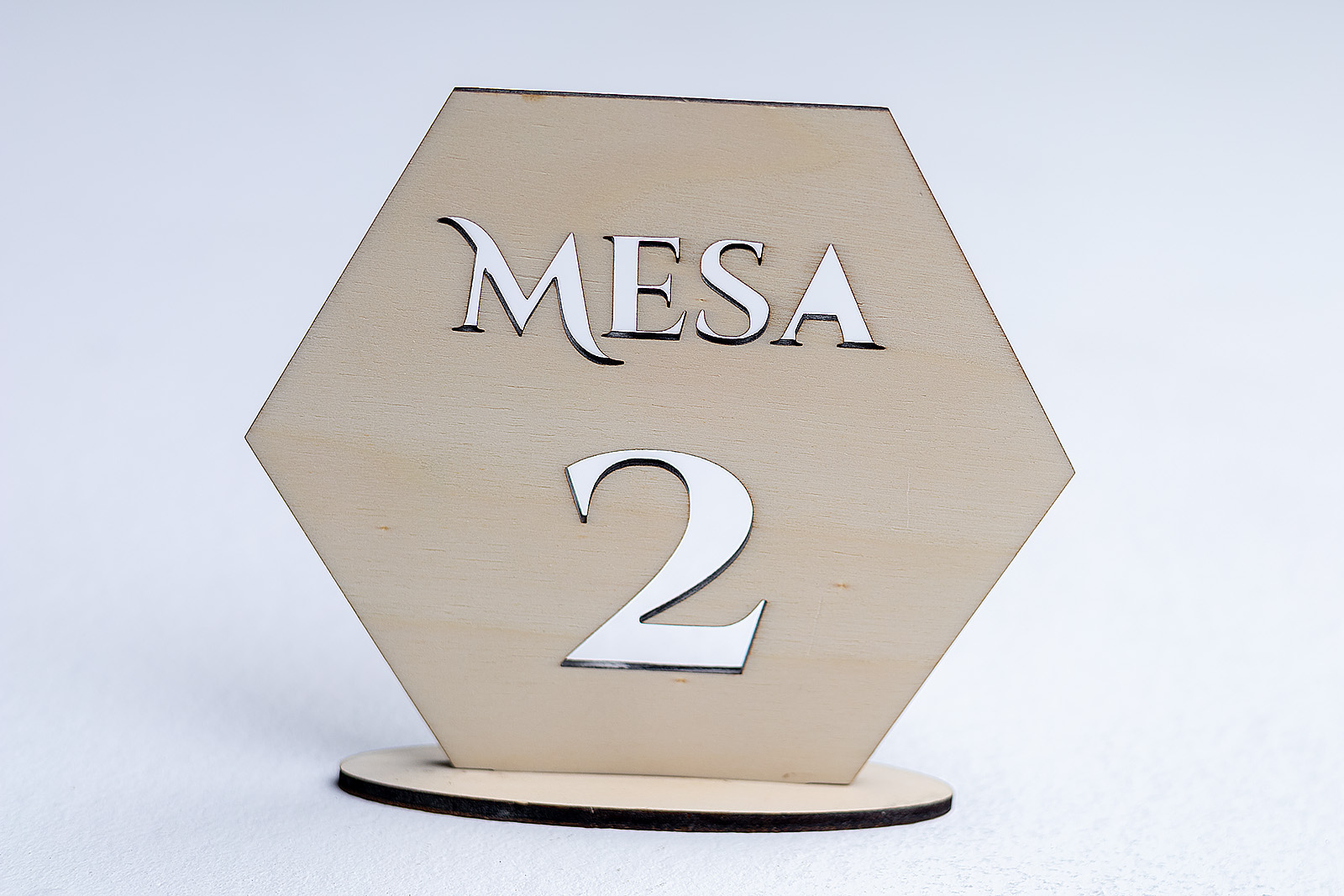 Numerador de mesa moderno en madera con forma hexagonal y número calado, ideal para decoración de eventos y bodas.