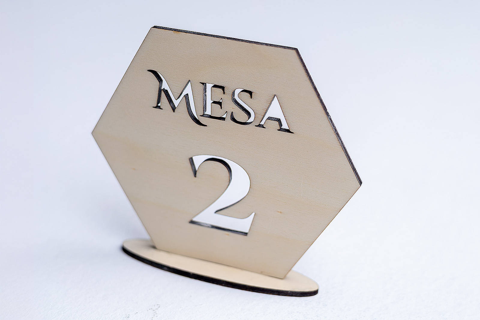 Vista lateral de un mesero de madera hexagonal mostrando el efecto 3D del número calado y la base de soporte.