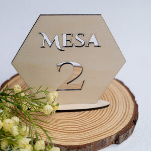 Número de mesa hexagonal de madera para boda, con diseño moderno calado del número 2 y decoración floral blanca y verde.