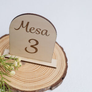 Número de mesa de madera con forma de arco para boda, grabado con el número 3 y decorado con flores blancas para un estilo romántico.