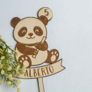 Topper de madera para tarta de cumpleaños con diseño de oso panda y nombre Alberto, presentado con flores para una decoración natural.