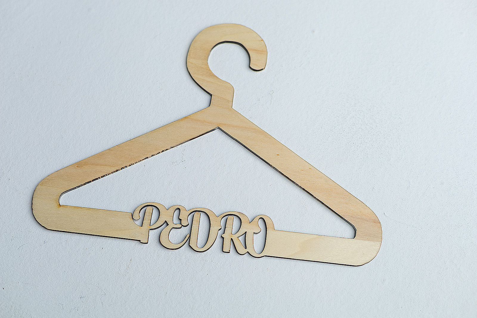 Percha infantil de madera personalizada con el nombre "Pedro" cortado a láser como parte de la barra inferior de la percha.