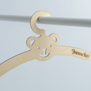 Percha infantil de madera con forma de oso colgada en una barra, personalizada con el nombre Juancho grabado a láser.