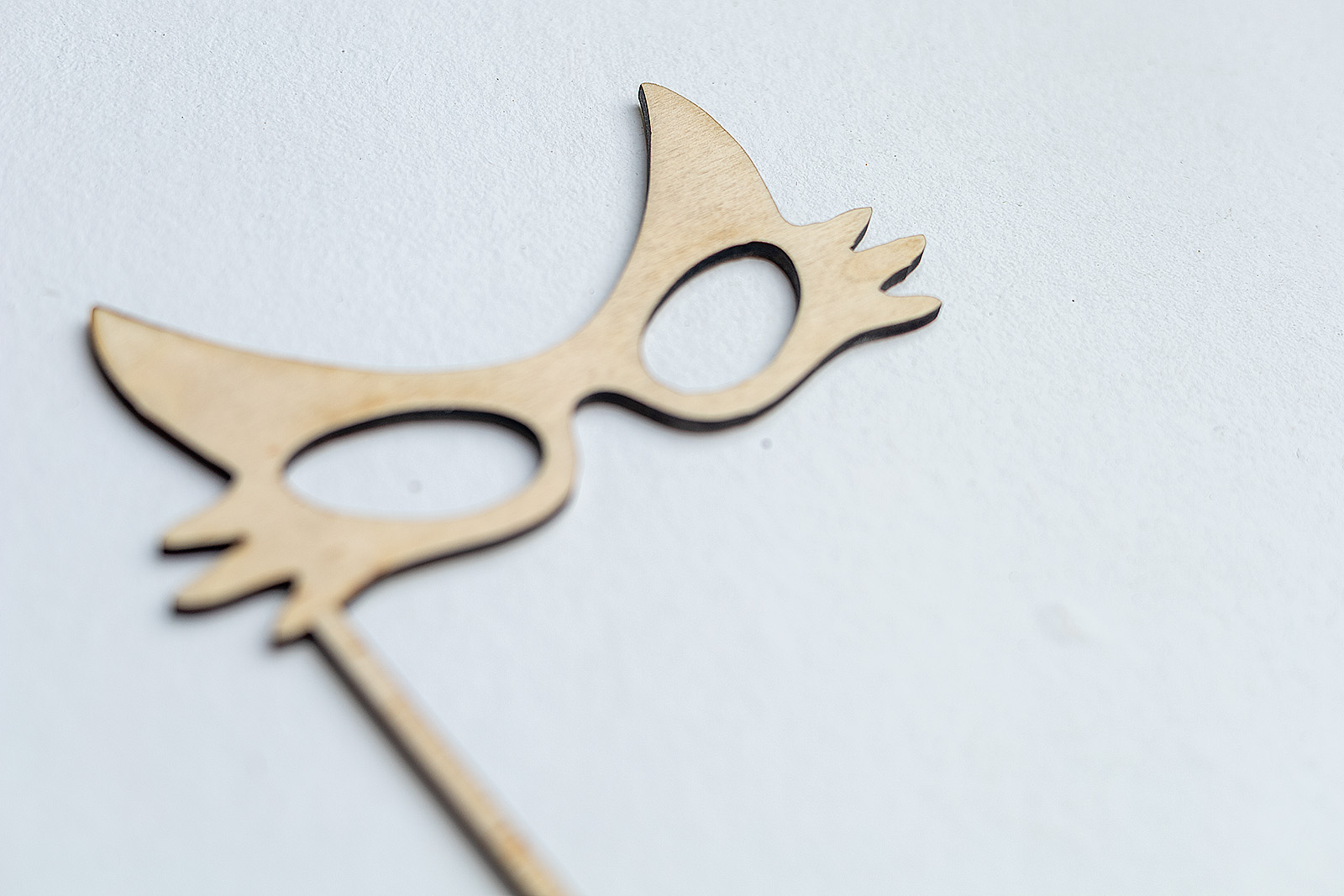 Primer plano de una máscara de gato de madera sin tratar, perfecta para pintar y personalizar como manualidad o disfraz.