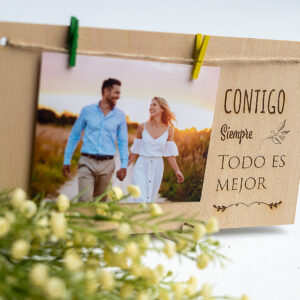 Primer plano del grabado en madera "Contigo siempre todo es mejor" en un portafotos rústico, ideal para regalo de aniversario o San Valentín.