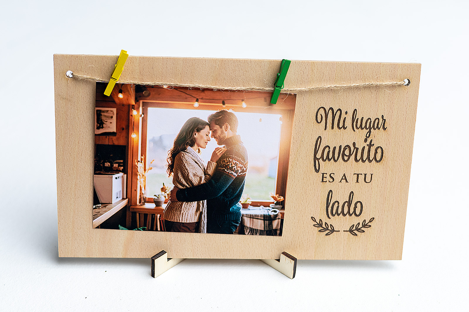 Portafotos de madera con la frase romántica "Mi lugar favorito es a tu lado" grabada, y una foto de una pareja abrazada colgada con pinzas.