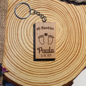 Llavero de bautizo de madera con un tierno grabado de piececitos, personalizado con el nombre Paula.