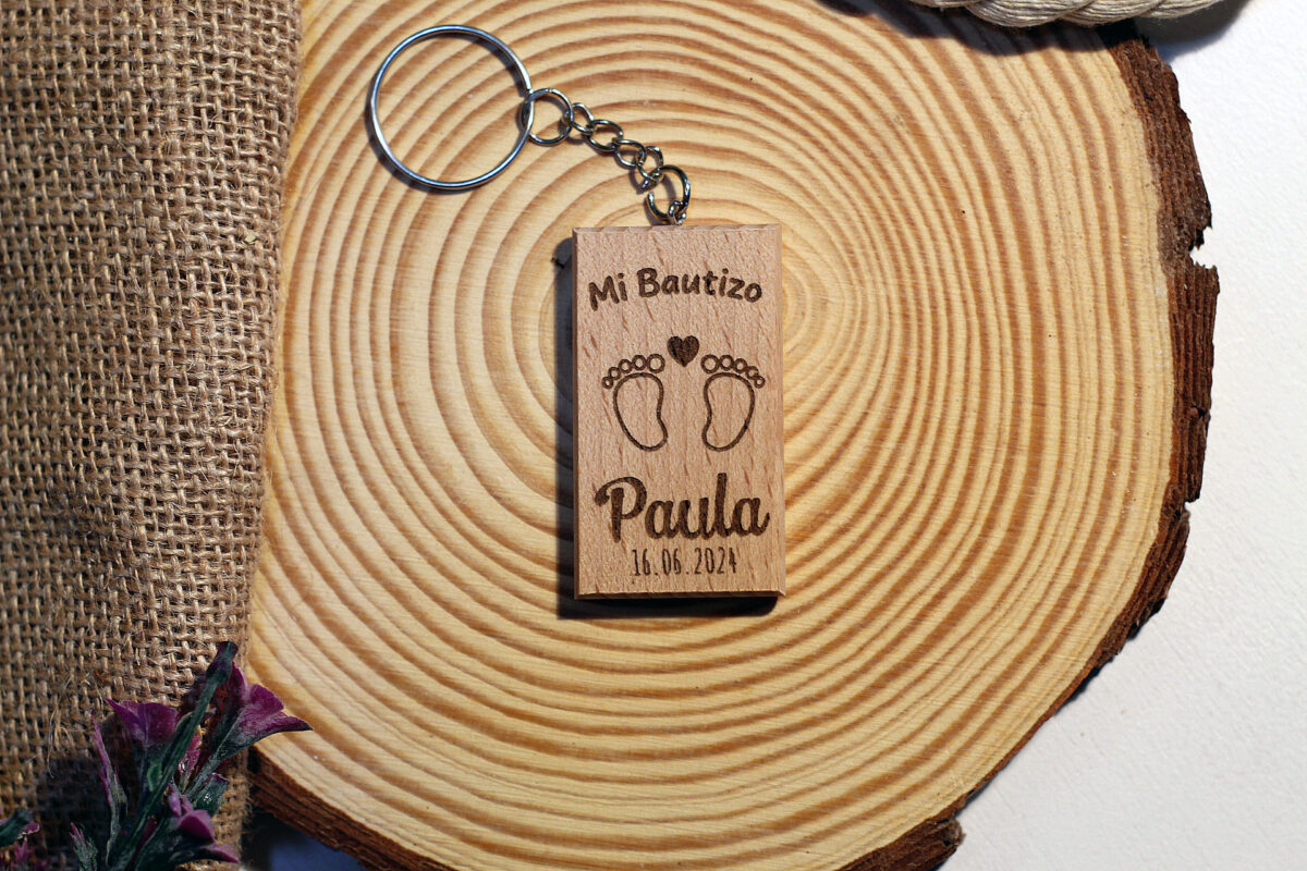 Llavero de bautizo de madera con un tierno grabado de piececitos, personalizado con el nombre Paula.