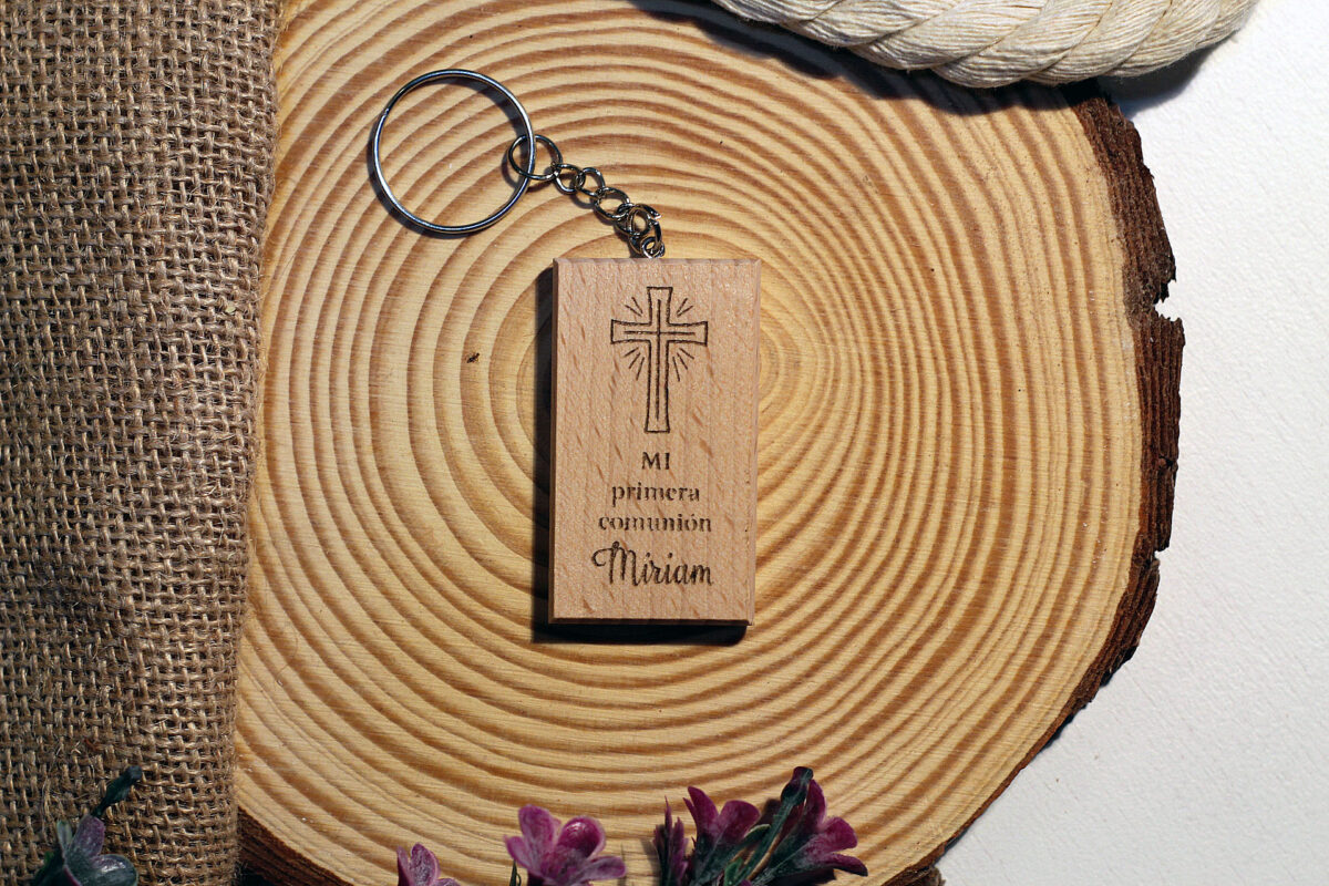 Llavero de madera personalizado para invitados de comunión, con diseño de cruz grabado, sobre una base de madera rústica.