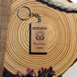 Llavero de madera rectangular como regalo para invitados de boda, personalizado con un globo aerostático, la frase "Nuestro Gran Día" y los nombres de los novios, en presentación rústica.
