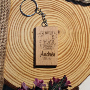 Llavero de madera para recuerdo de bautizo con diseño del Arca de Noé y nombre Andrés, presentado sobre una rodaja de tronco y tela de saco para un estilo rústico.