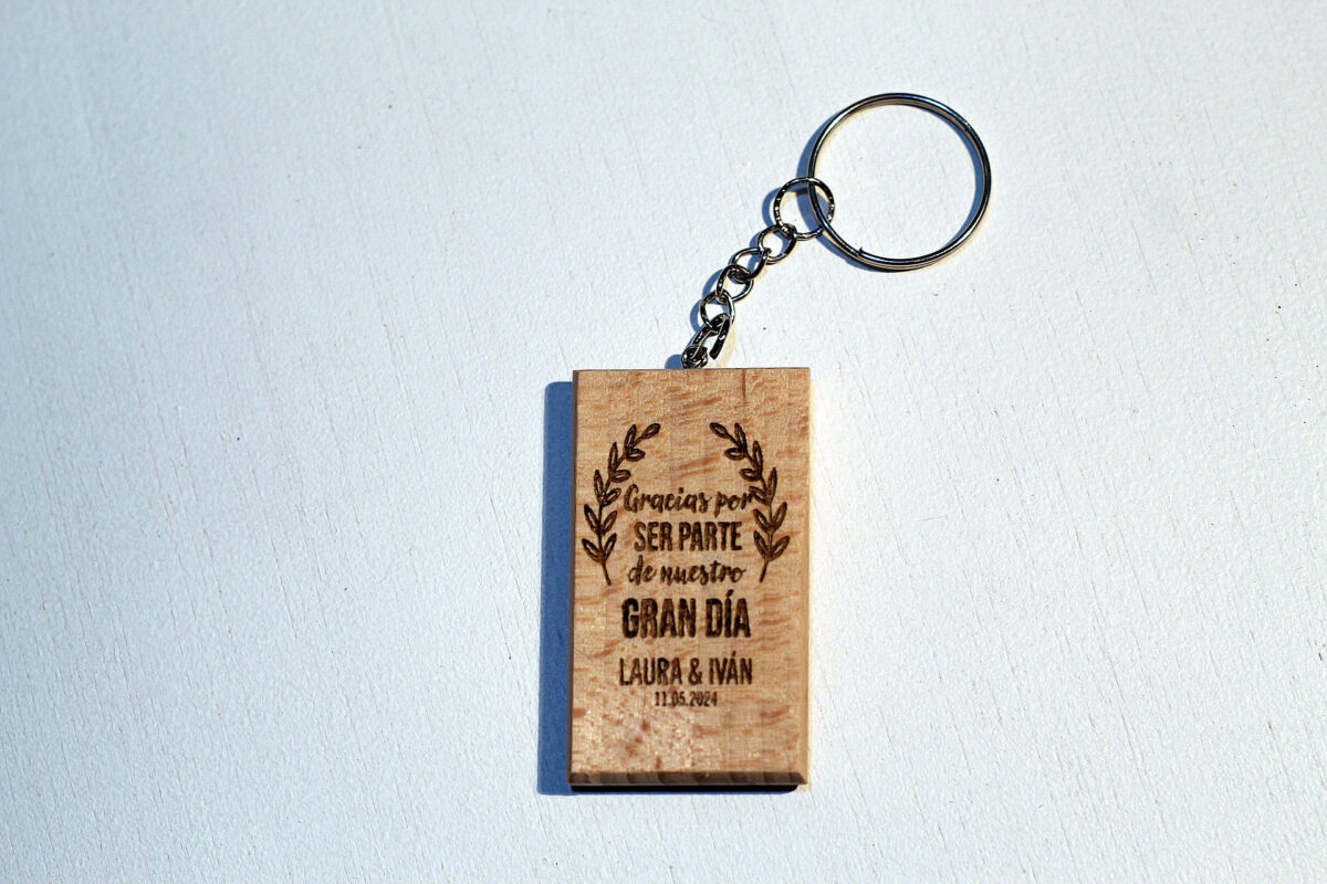 Vista frontal de un llavero de madera para invitados, grabado con una frase de agradecimiento y fecha de boda, diseño elegante con ramas.