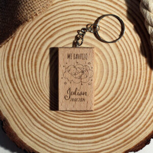 Llavero de madera rectangular personalizado para bautizo, grabado con un bebé durmiendo sobre una nube y el nombre Julian, presentado sobre una rodaja de madera.