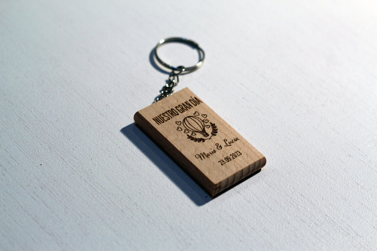 Llavero de madera para invitados de boda, grabado con un globo aerostático y la frase "Nuestro Gran Día", personalizado con los nombres Mario y Lucía.