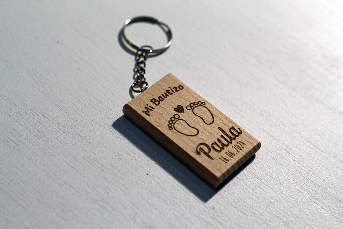Detalle del grabado láser del llavero de bautizo con piececitos, mostrando su definición.
