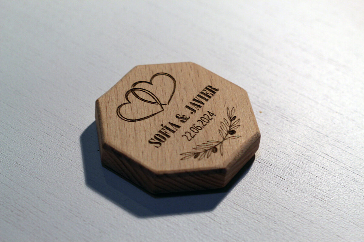 Recuerdo de boda práctico: Abrebotellas con imán de madera octogonal, grabado con dos corazones entrelazados y personalizado con los nombres de los novios y la fecha.
